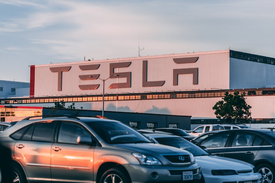 GM Factory Zero üretim durduruyor: Elektrikli araç sektörü krizi — Tesla factory with parked cars during sunset, showcasing modern automotive indus