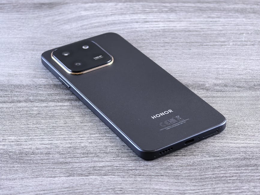 Honor 600 serisi iPhone 17 Pro tasarımını kopyalıyor, 9000 mAh bataryayla geliyor — Close-up of a modern smartphone with a sleek design on a wooden surface.