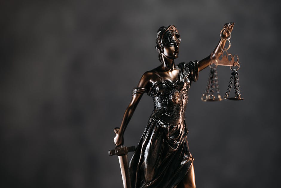 Üç YouTube kanalı Apple'a telif ihlali davası açtı: AI eğitim sürecinde izinsiz video kullanımı — Detailed bronze Lady Justice statue with scales and sword against a dark backgro