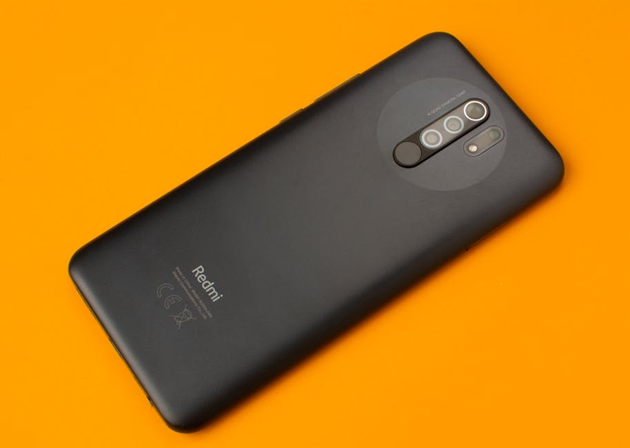Xiaomi Redmi Note 15 SE: Bütçe Telefonlarda AI Özellik Devrimi — Black smartphone placed on a vivid orange background, showcasing sleek design an