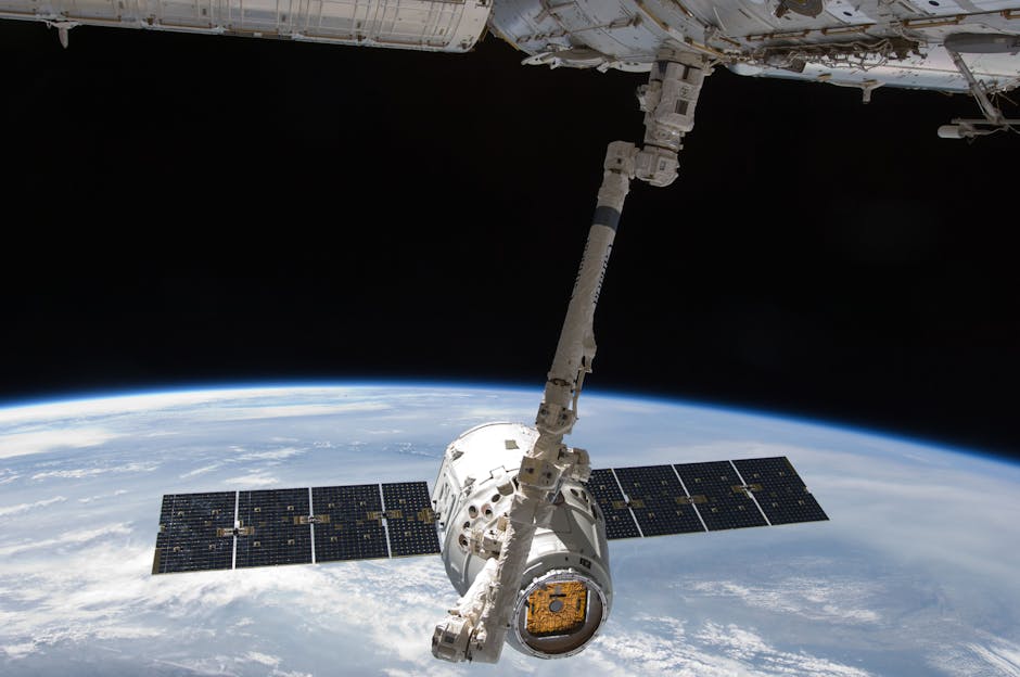 NASA astronotlarının uzay şakaları yazılım güvenlik açıklarını ortaya çıkardı — View of a spacecraft docked at the ISS above Earth with visible solar panels.